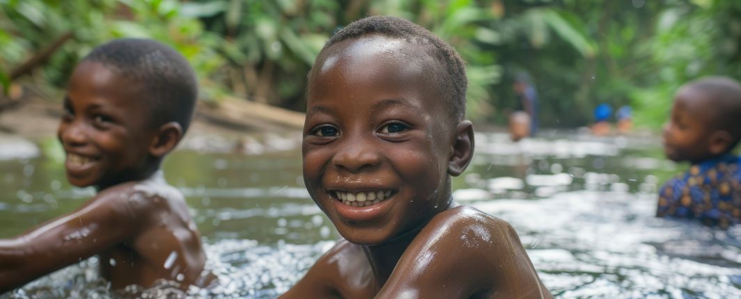 Niños sonriendo mientras se bañan en un río.