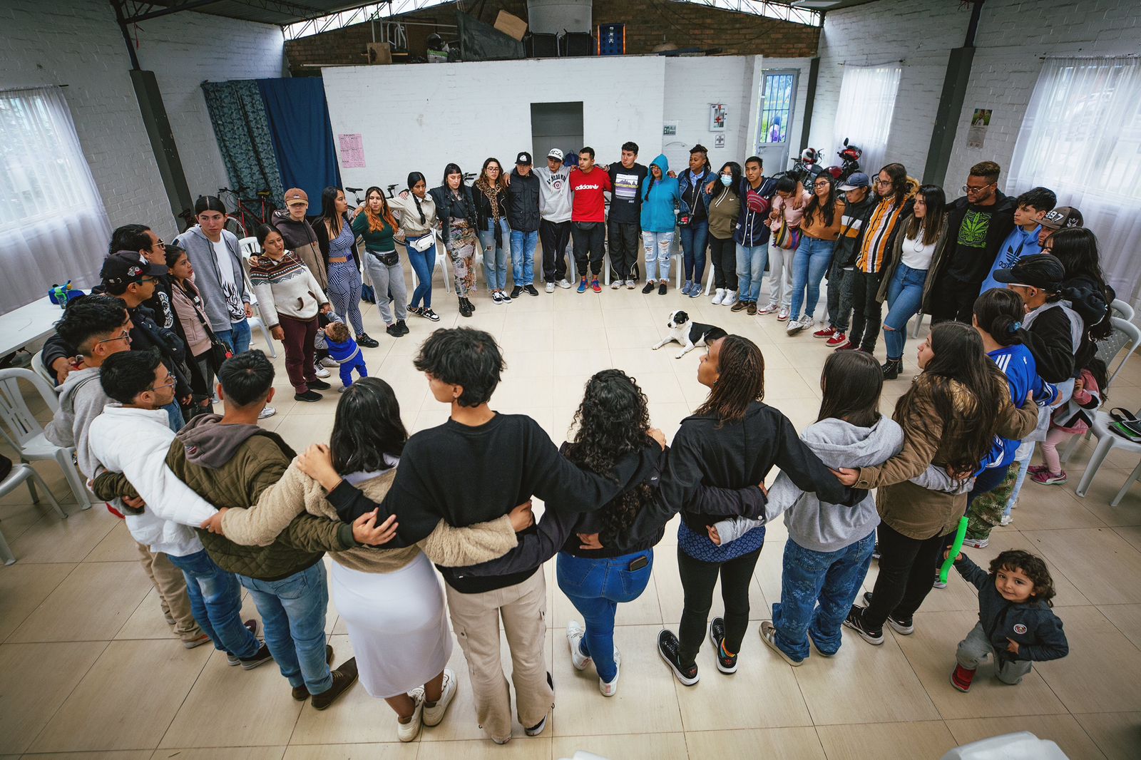 Grupo de personas del programa Jóvenes en Paz reunidas y abrazadas en círculo.